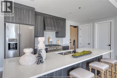 A kitchen with a white counter top and a stainless steel refrigerator.