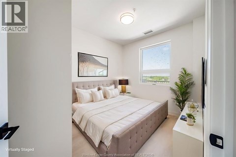 A bedroom with a large bed and a painting on the wall.