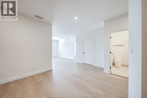 A spacious room with a white door and a white bucket on the floor.