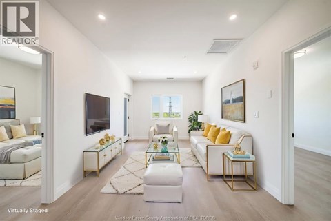 A virtual staging of a real estate listing shows a modern living room with a white sofa, gold side table, and a large window.