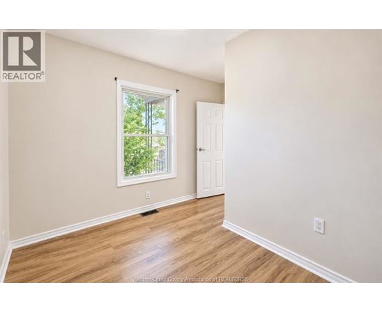 A room with a window and a door is empty and waiting to be furnished.