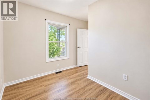 A room with a window and a door is empty and waiting to be furnished.