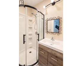 A bathroom with a white sink and a mirror with a black frame.