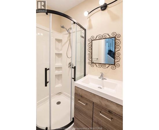 A bathroom with a white sink and a mirror with a black frame.