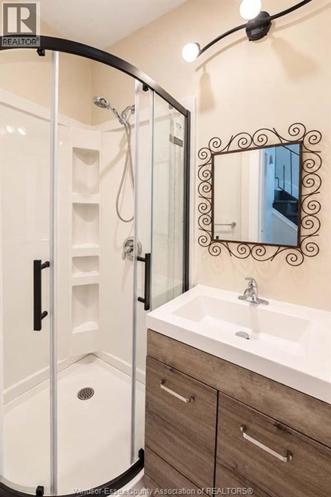 A bathroom with a white sink and a mirror with a black frame.
