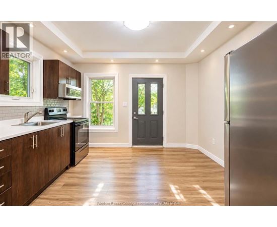 A kitchen with wooden cabinets and a black door.