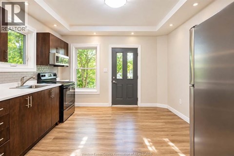 A kitchen with wooden cabinets and a black door.