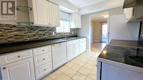 A kitchen with white cabinets and a stone backsplash.