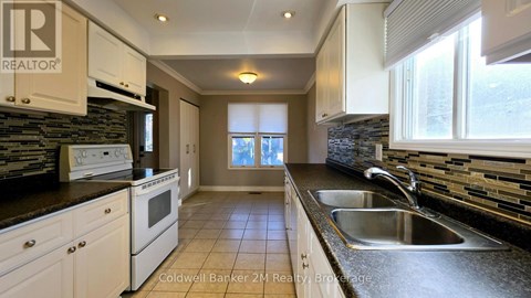 A kitchen with white cabinets and a stone backsplash.
