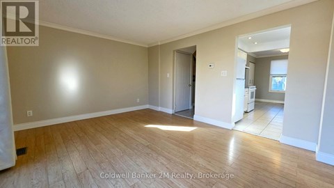 A spacious room with wooden flooring and a doorway leading to another room.