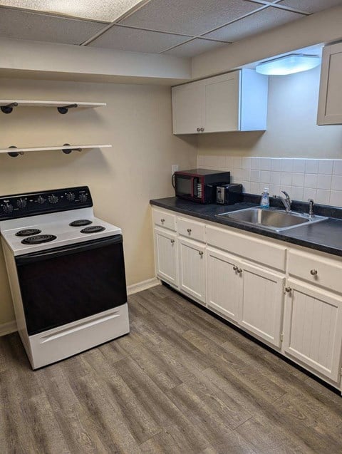 A kitchen with a black stove top oven and white cabinets.