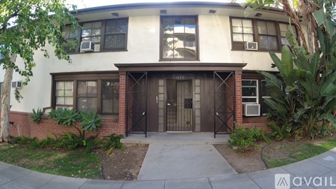 A two-story building with a white and brown facade and a black gate.