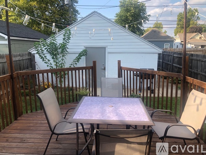 A patio with a table and chairs is set up on a wooden deck.
