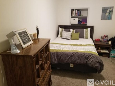 A bedroom with a bed, nightstand, and a dresser.