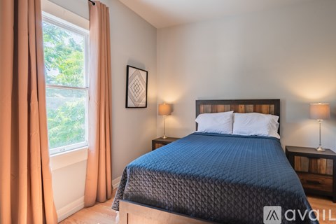 A bedroom with a large bed and a window with curtains.
