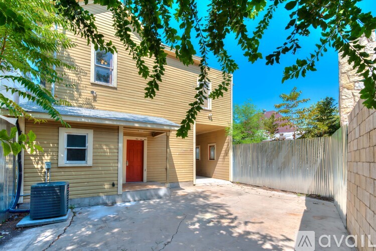 A house with a red door is surrounded by a wooden fence.