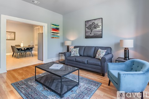 A living room with a grey couch, a blue armchair, and a glass coffee table.