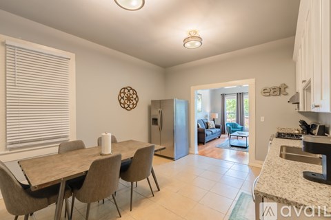 A kitchen with a table and chairs in the foreground and a refrigerator in the background.