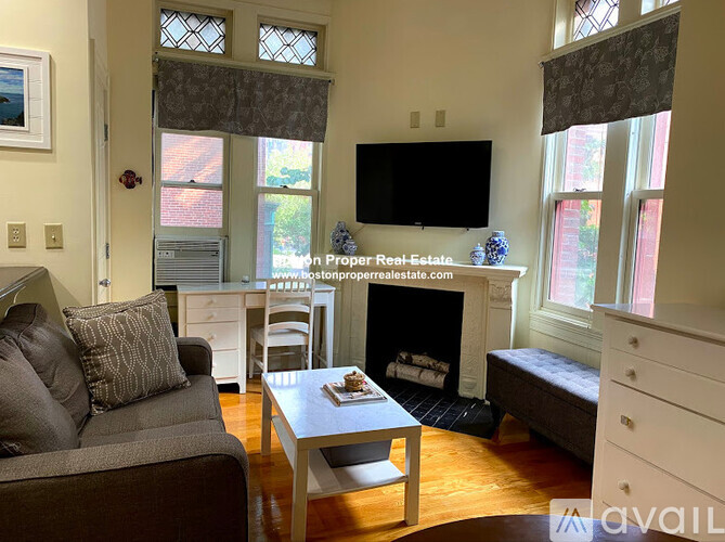 A living room with a grey couch, a white coffee table, and a fireplace.