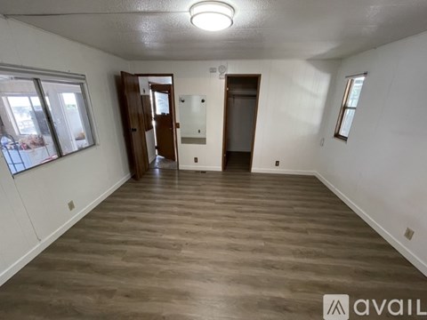 A spacious room with wooden flooring and white walls.