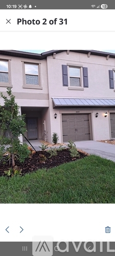 A two-story house with a garage and a tree in front.