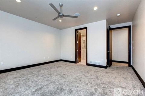 A spacious room with a ceiling fan and carpeted floor.