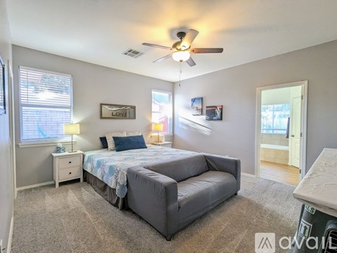 A bedroom with a bed, a couch, and a ceiling fan.