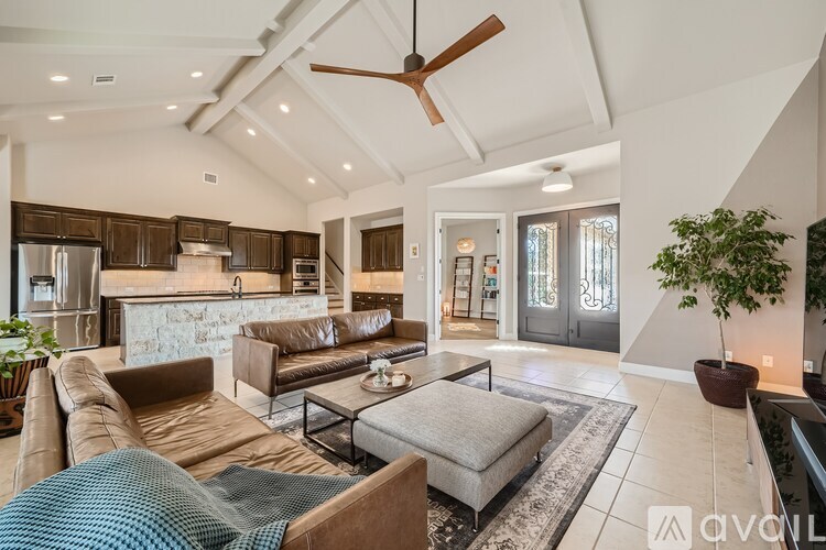 A modern living room with a brown leather couch and a ceiling fan.