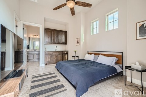 A bedroom with a large bed and a ceiling fan.
