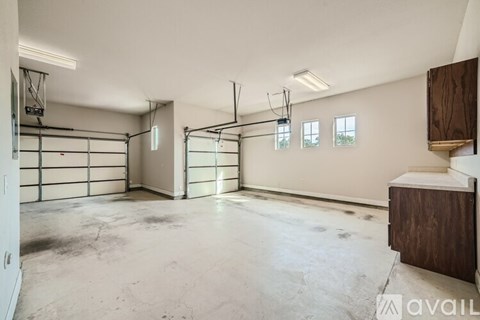 A spacious garage with a white ceiling and a brown cabinet.