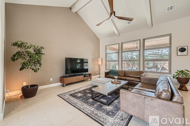 A living room with a brown leather couch, a wooden coffee table, and a ceiling fan.