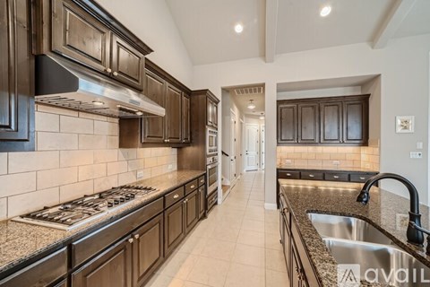 A kitchen with dark wood cabinets and a stainless steel sink.