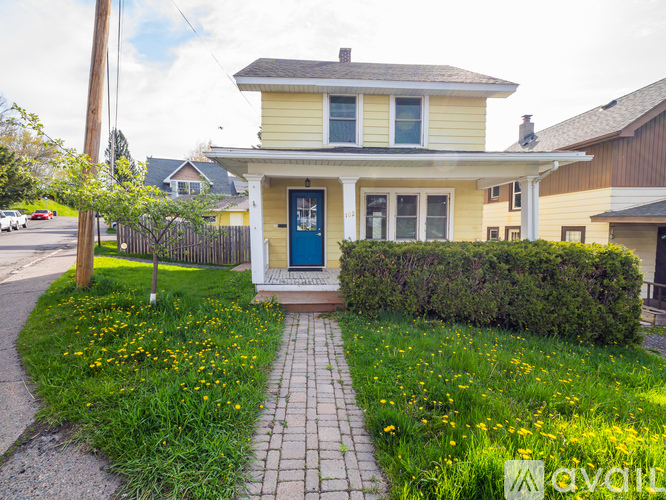 A yellow house with a blue door and a green lawn in front.