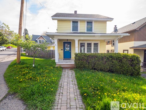 A yellow house with a blue door and a green lawn in front.