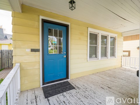 A yellow house with a blue door and a black mat in front of it.