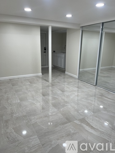 A spacious room with marble flooring and a glass door.