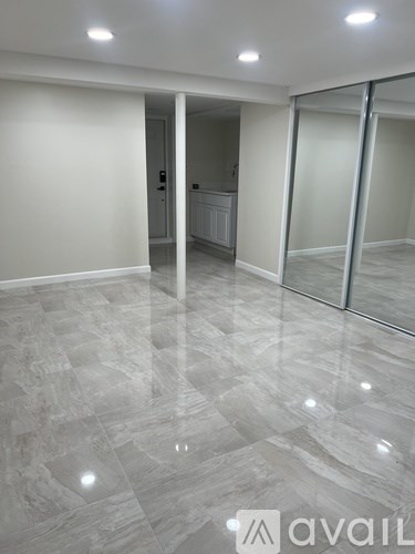 A spacious room with marble flooring and a glass door.