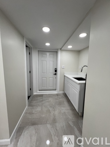 A hallway with a white door and a counter on the right side.