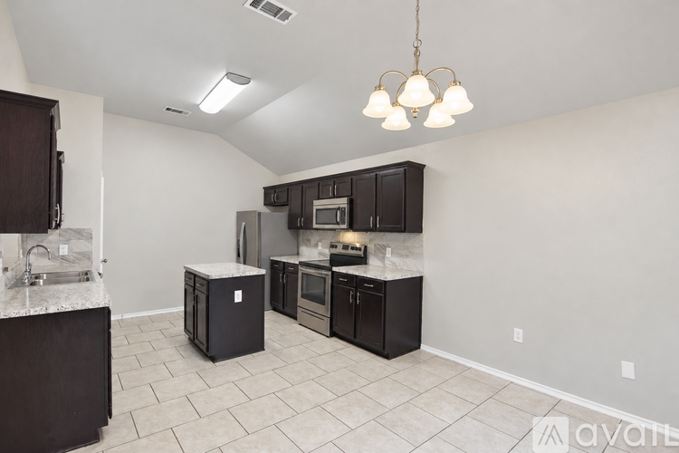 A kitchen with black cabinets and a white island.