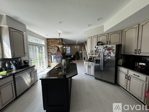 A kitchen with a black island in the middle and a brick wall.