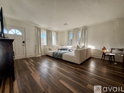 A living room with a white sofa and wooden flooring.