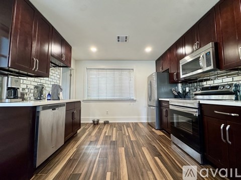 A kitchen with dark wood floors and modern appliances.