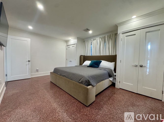 A bedroom with a large bed and a carpeted floor.