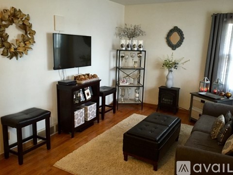 A living room with a television, a wreath, and a glass vase with flowers.