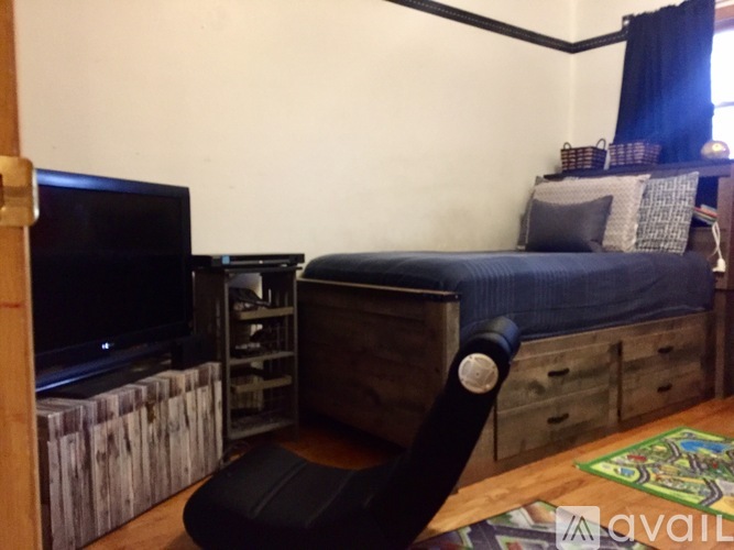 A bedroom with a bed, a chair, and a television.
