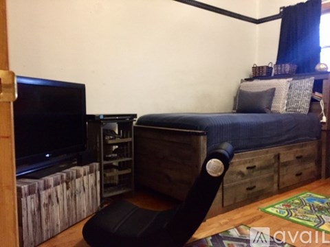 A bedroom with a bed, a chair, and a television.