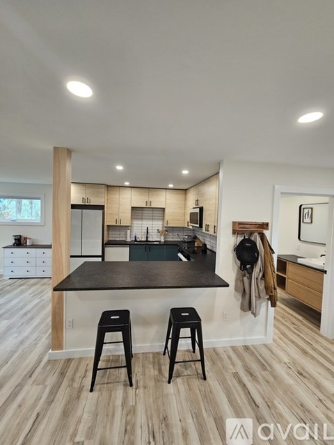 A kitchen with a black countertop and bar stools.