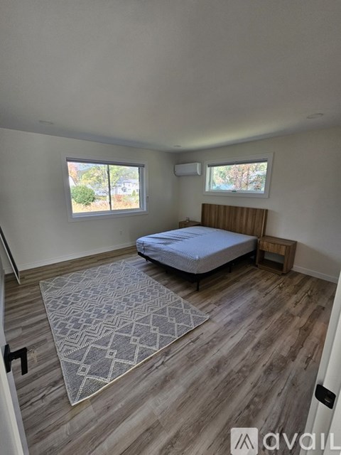 A bedroom with a bed, window, and wooden flooring.