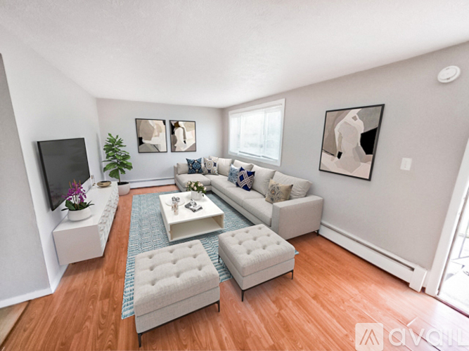 A living room with a white couch, a white coffee table, and a white ottoman.