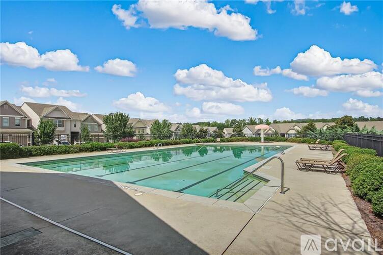 A large outdoor swimming pool surrounded by a concrete deck and lounge chairs.